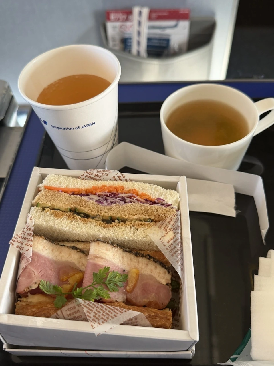 ANAのプレミアムクラスの軽食。箱に入ったサンドイッチと、スープと飲み物のカップ