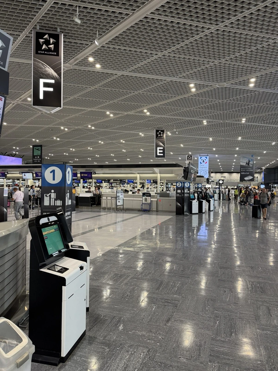 成田空港第1ターミナルの出発ロビー。スターアライアンスのF・Eの案内と、並んだ自動チェックイン機