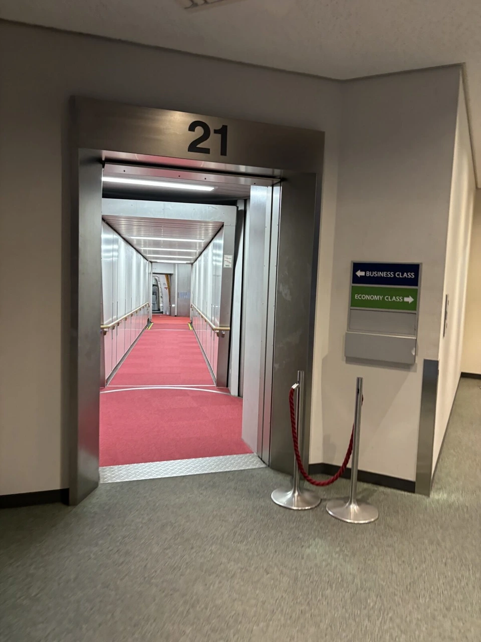 成田空港第1ターミナル21番搭乗口の搭乗橋。ビジネスクラスとエコノミークラスの案内板