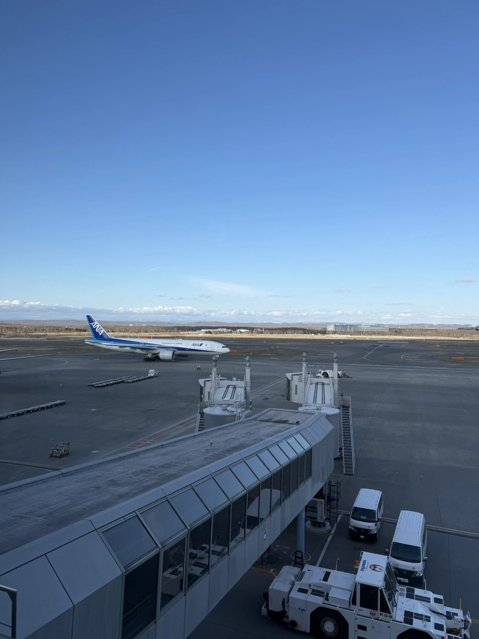 晴れた日の新千歳空港。ターミナルの先の誘導路を走るANAの機体