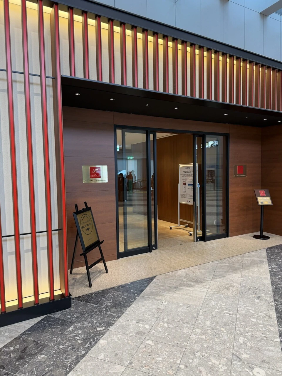 新千歳空港のJAL FIRST CLASSの表示がある入口と、SKYTRAXの5スターの看板
