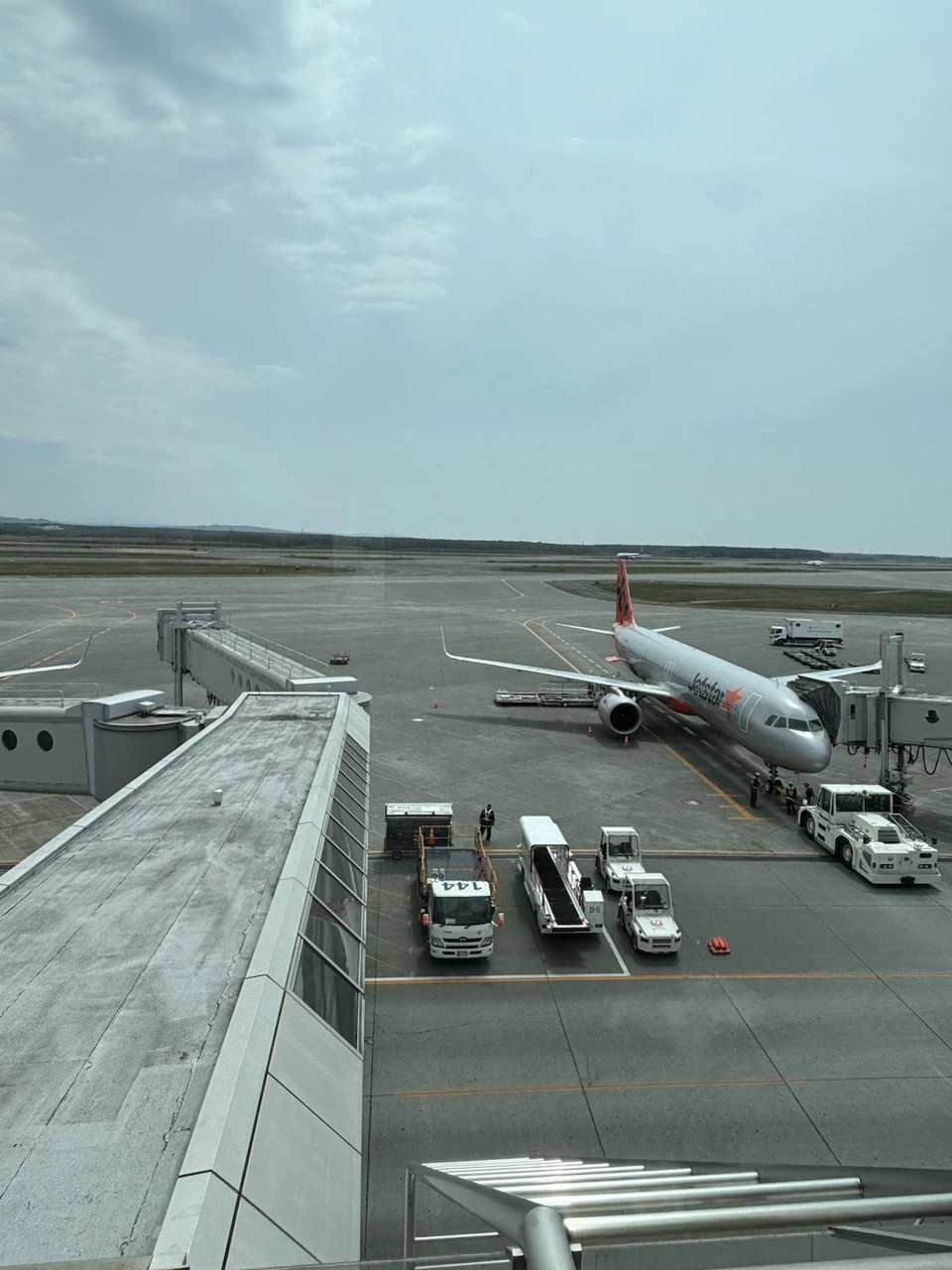 新千歳空港のターミナルから見た駐機場。ボーディングブリッジにつながる飛行機と地上の車両