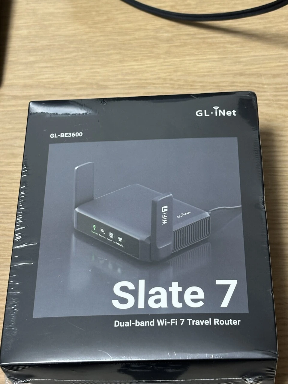 ビニールに包まれたままのGL.iNet Slate 7の黒い箱。GL-BE3600の型番と、Dual-band Wi-Fi 7 Travel Routerの文字
