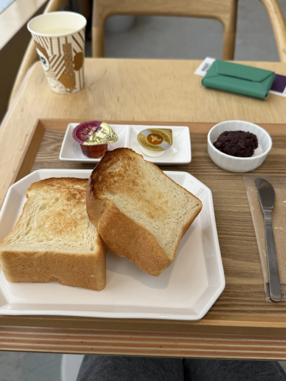 カフェのテーブルの朝ごはん。厚切りトースト2枚とあんこ、メープルシロップ、北海道バター。奥にエメラルドグリーンのMOFTのカードケース