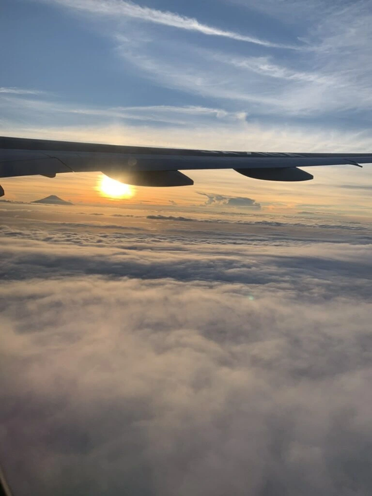 ANA1097便(羽田→那覇)の機窓から見た主翼と、雲海の上に沈む夕日