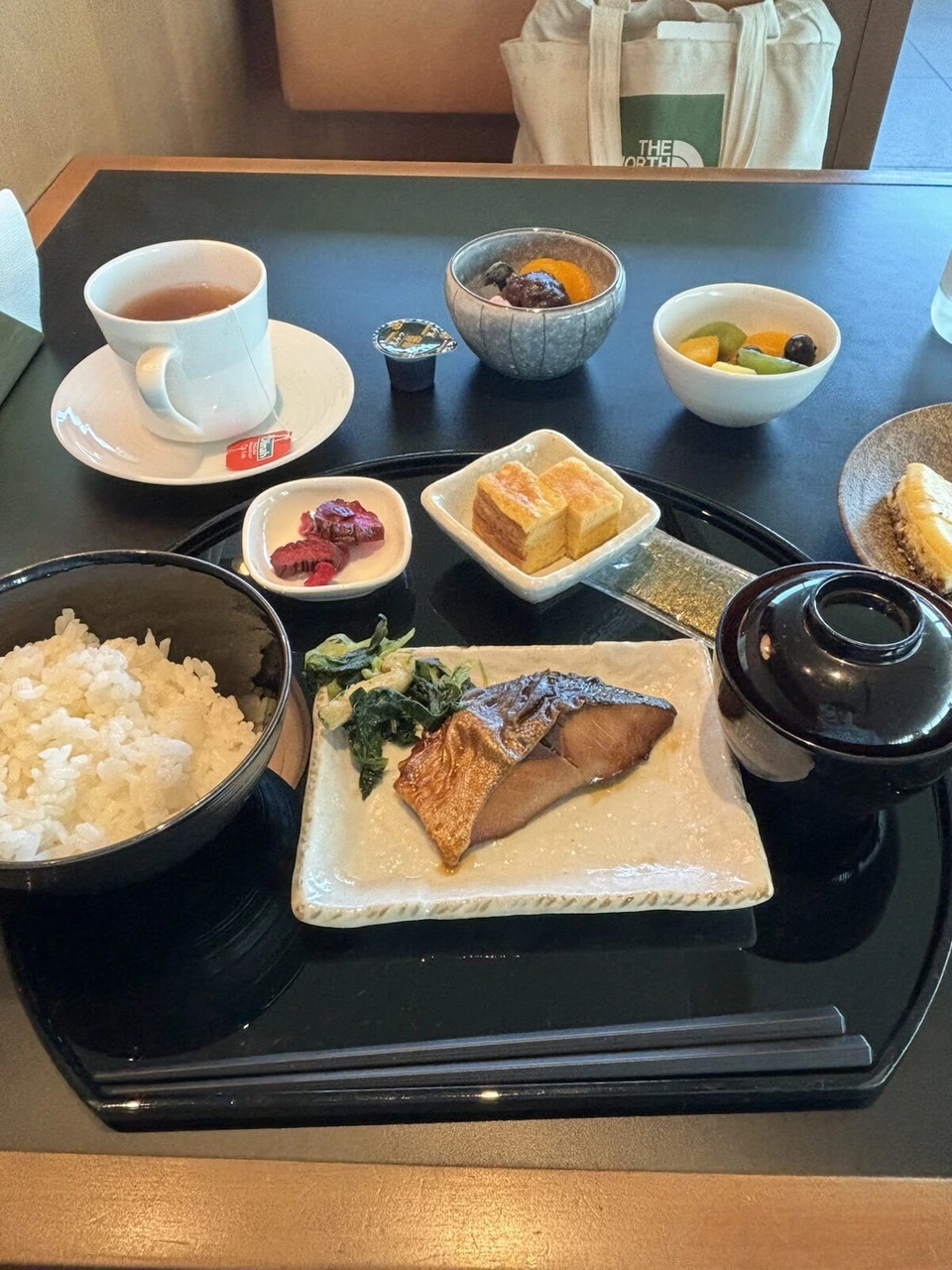 羽田第3ターミナルのJALラウンジの朝食。焼き魚、卵焼き、ご飯、味噌汁、漬物、果物、チーズケーキと紅茶