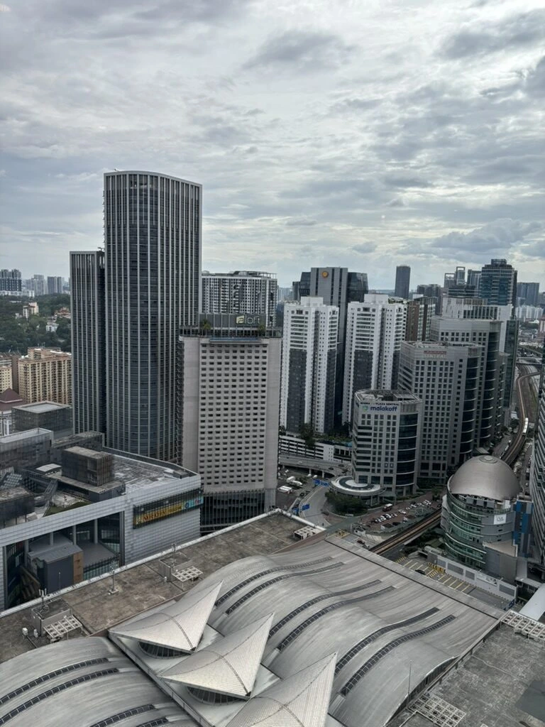 AC Hotel Kuala Lumpurの高い階の窓から見たクアラルンプールのビル群と、手前の波形の屋根