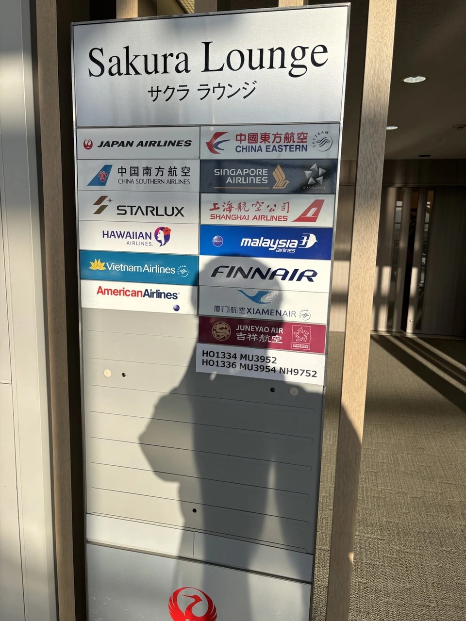 関西空港のサクララウンジの案内板。JAL、ハワイアン航空、マレーシア航空、フィンエアー、アメリカン航空などのロゴが並ぶ