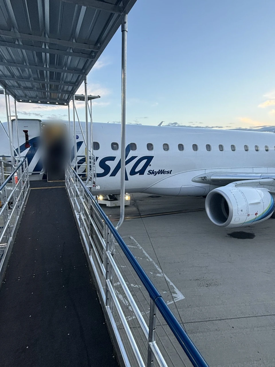 サンフランシスコ空港で、屋根付きの通路の先に止まるアラスカ航空（スカイウエスト運航）のE175