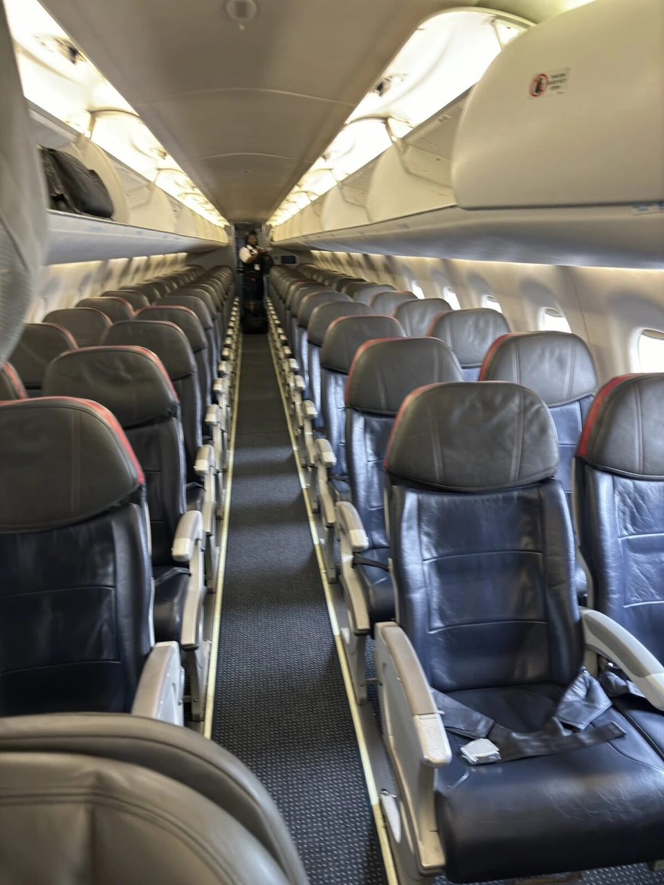 アメリカン航空のE175の客室。手前に革張りの座席が並び、奥まで通路が続く