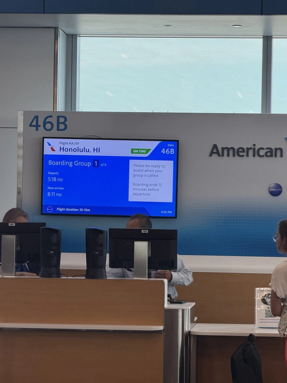 ロサンゼルス空港46Bゲートのアメリカン航空のカウンターと、ホノルル行きの案内画面。Boarding Group 1の表示