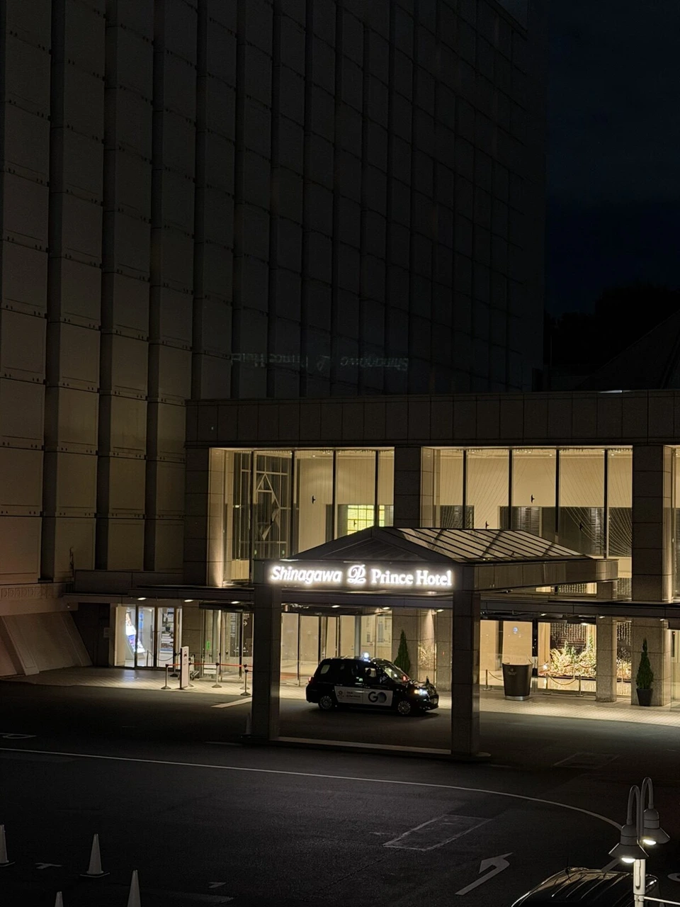 深夜の品川プリンスホテルの車寄せ。光るShinagawa Prince Hotelのサインとタクシー
