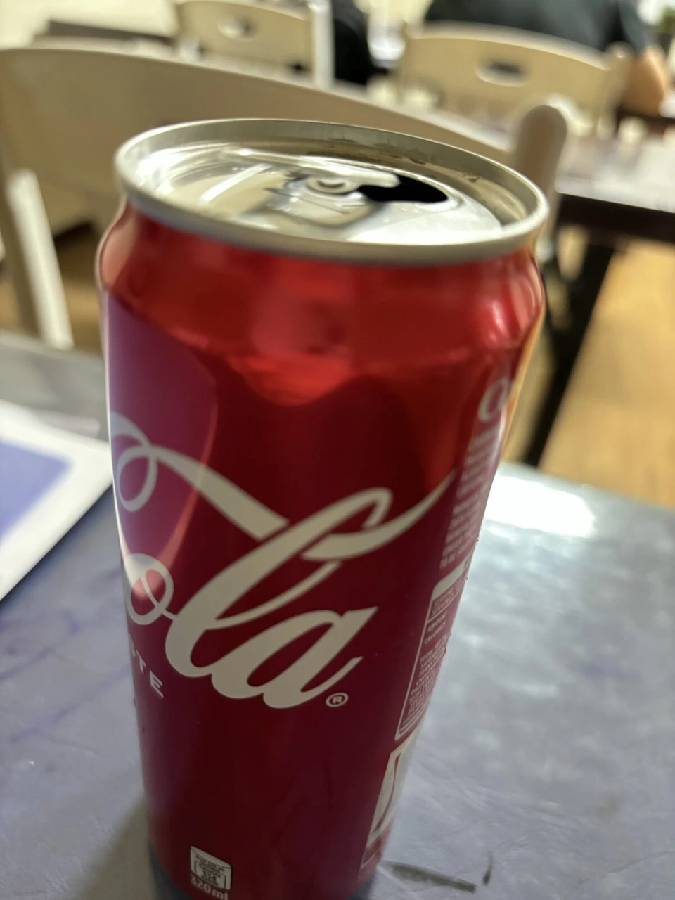 食堂のテーブルに置いたコカ・コーラの缶