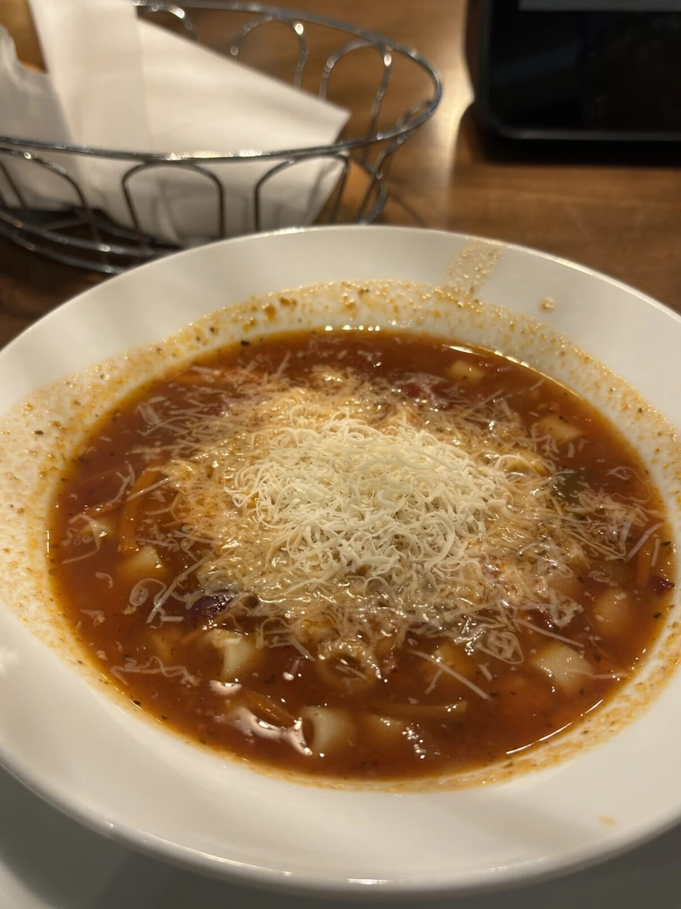 チーズをたっぷりかけたトマトベースのスープ