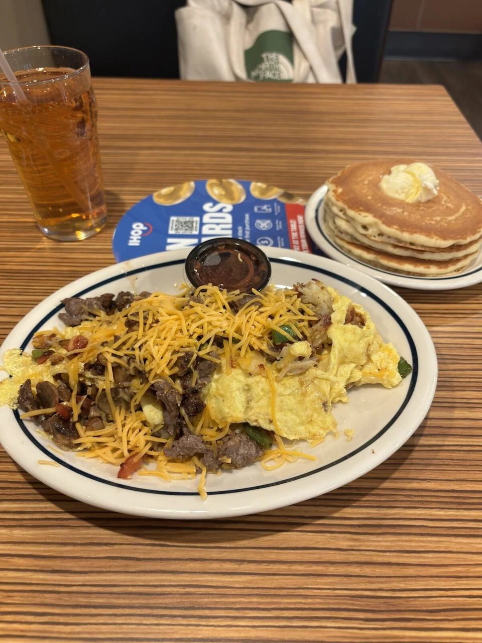 チーズがのったスクランブルエッグと牛肉、パンケーキとアイスティーの朝食