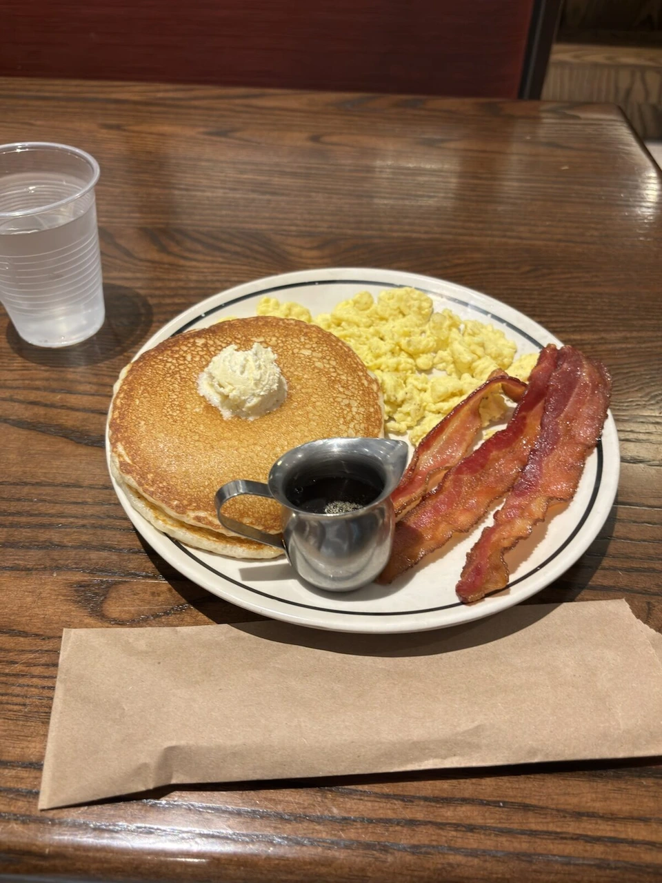 バターをのせたパンケーキ、スクランブルエッグ、ベーコンとシロップ
