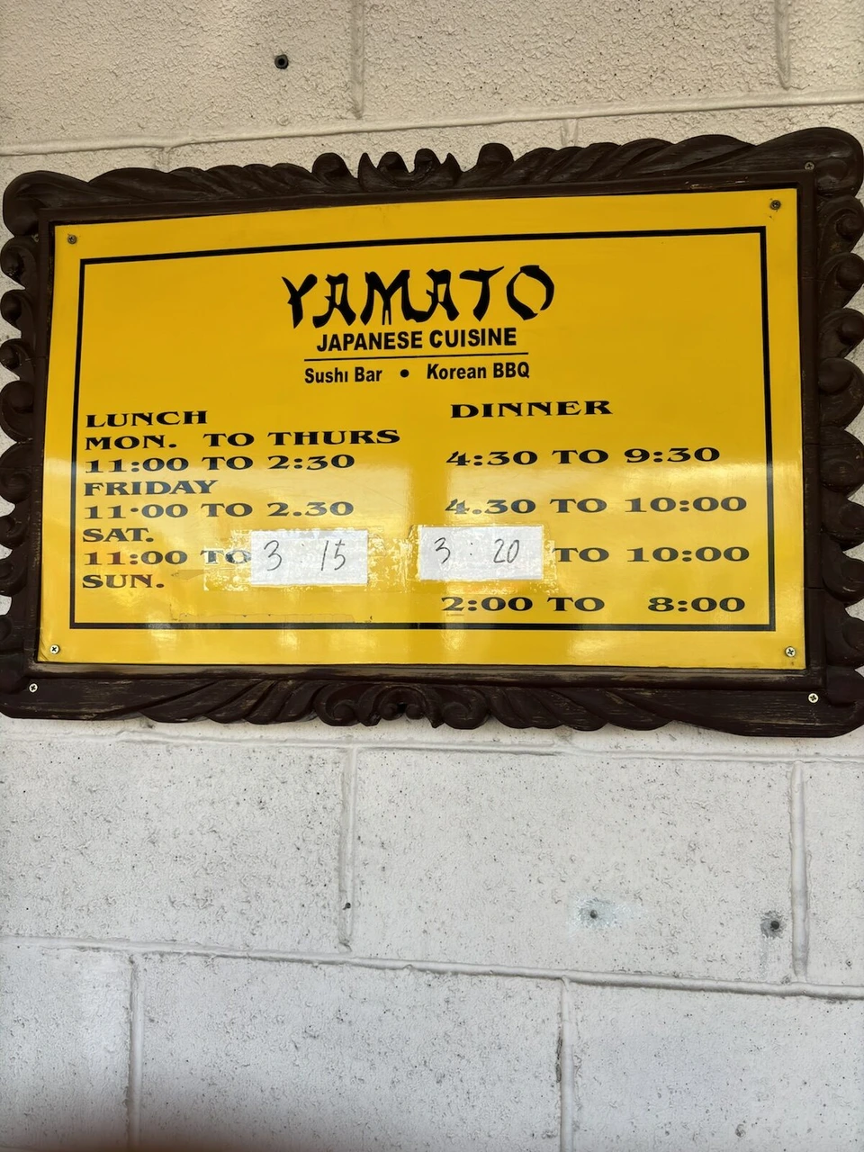 日本料理店YAMATOの黄色い営業時間の看板