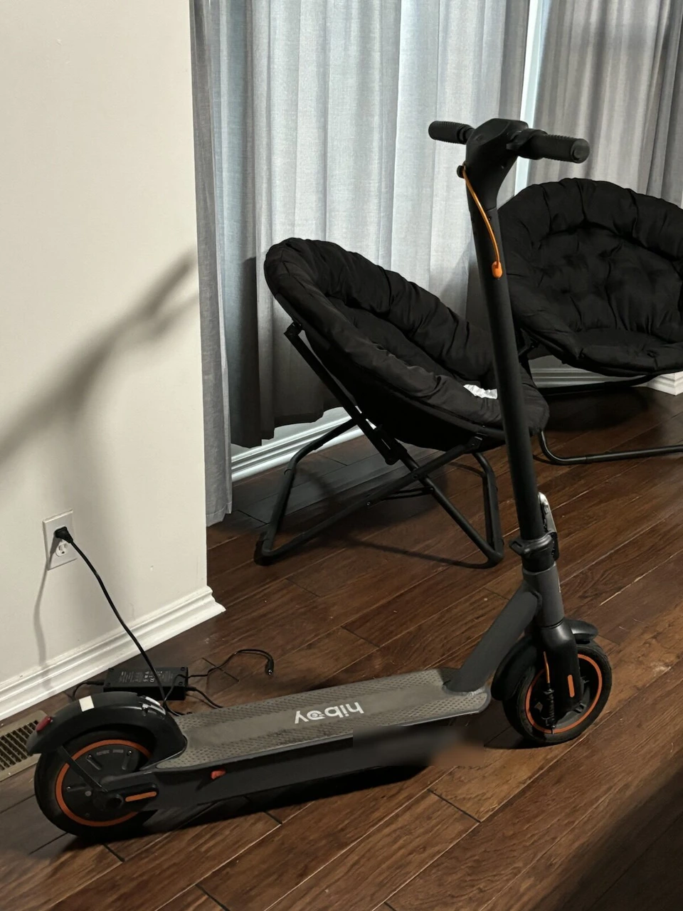 フローリングの部屋に置いた電動キックボードと、丸い折りたたみチェア2脚
