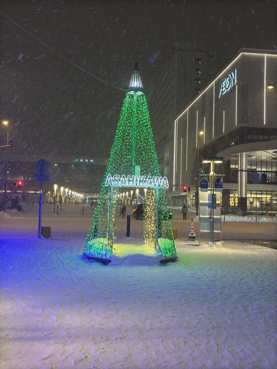 旭川駅前のツリー形のイルミネーションが、赤から緑色に変わったところ。足もとの雪も緑と青に照らされている