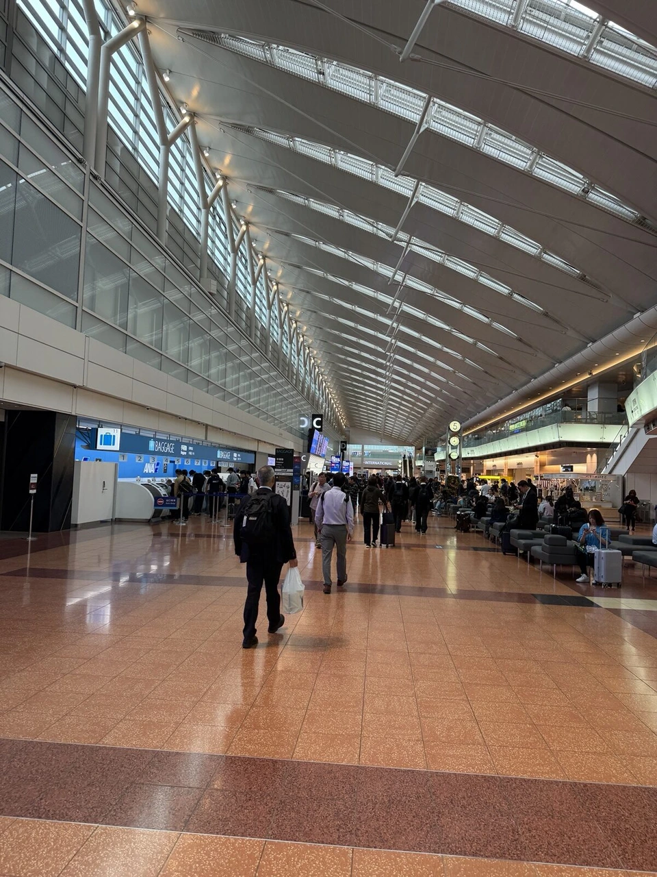 朝の羽田空港の出発ロビー。高い天井と長い通路