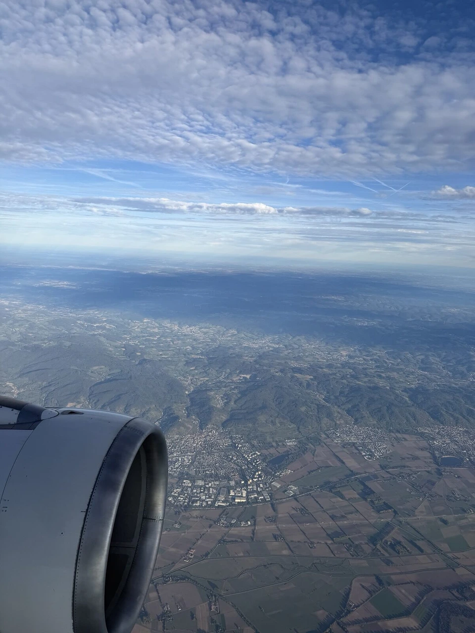 LH1196の機窓から見た雲と、その下の山あいの町