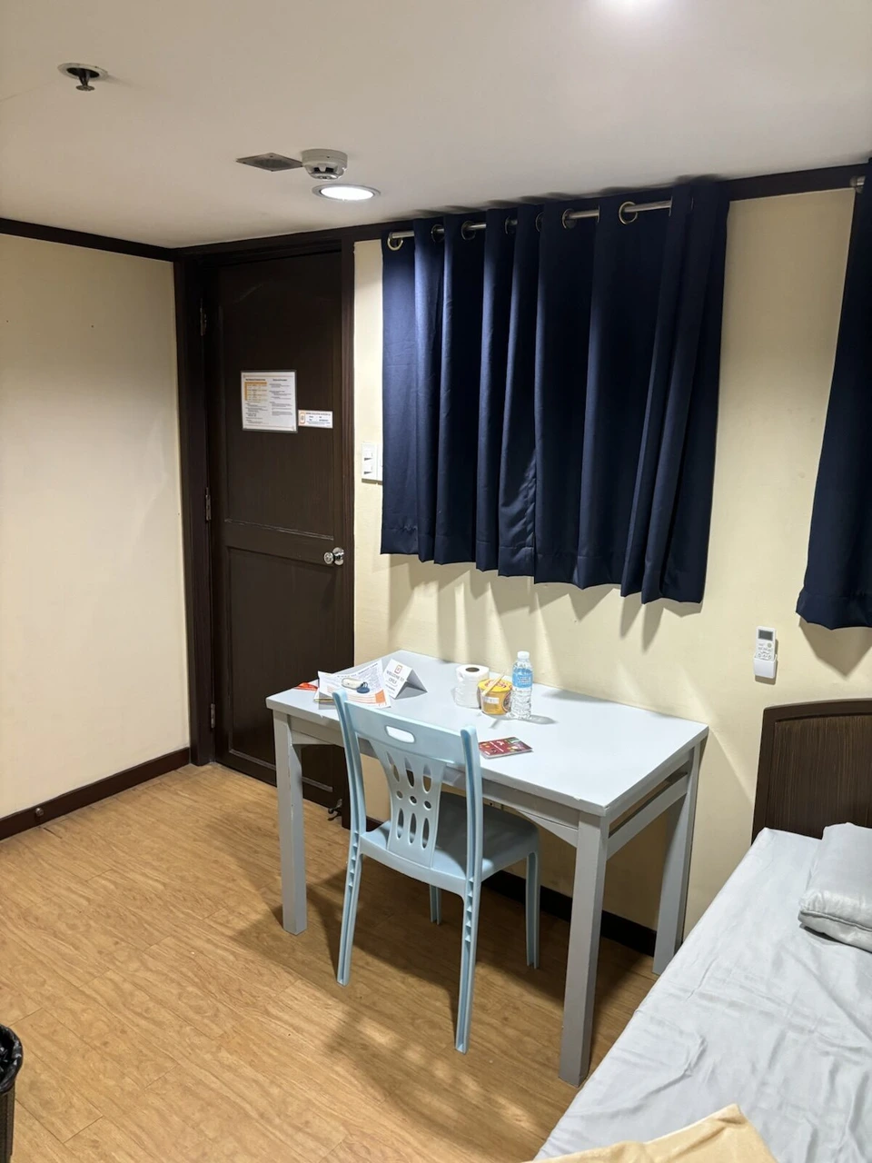 語学学校の寮の部屋。紺色のカーテン、白い机と水色の椅子、ベッド