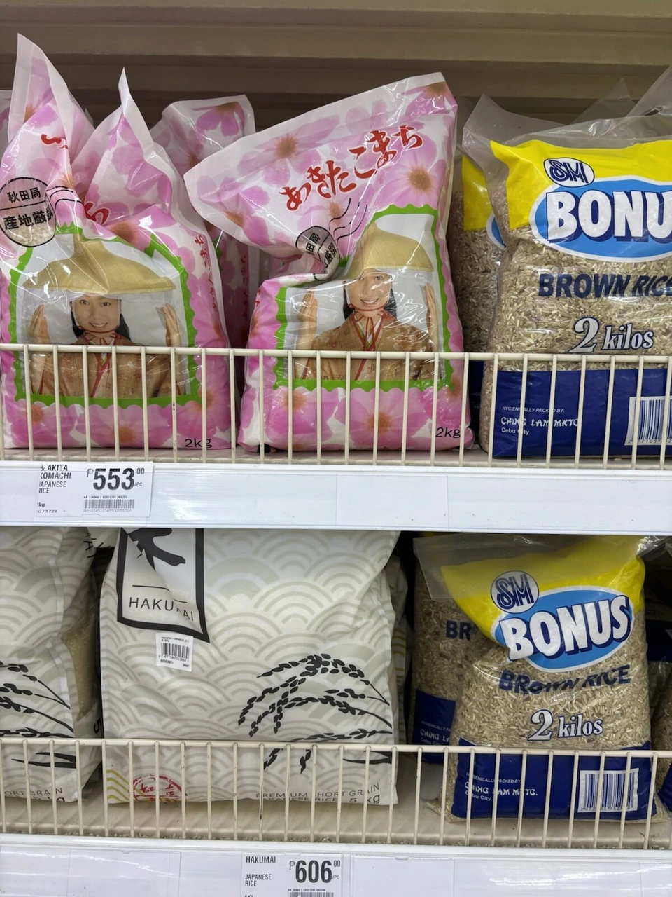スーパーの棚に並ぶ日本の米あきたこまちと現地の玄米