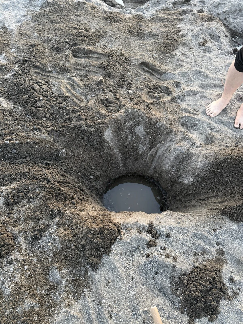 屈斜路湖の砂湯。砂浜に掘った穴にたまったお湯と、そばに立つ素足
