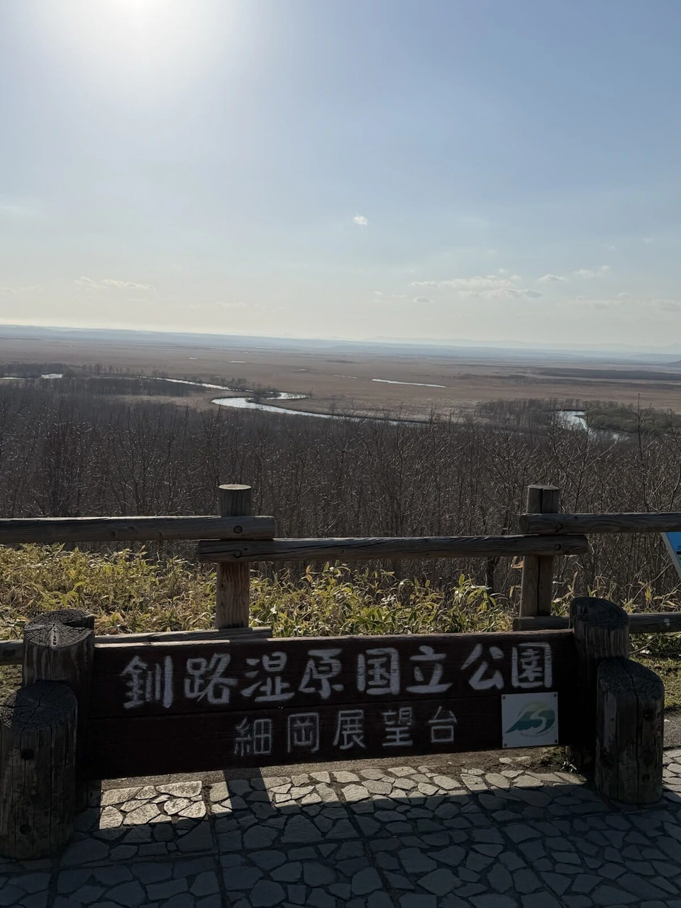 「釧路湿原国立公園 細岡展望台」の木の看板と、その奥の湿原