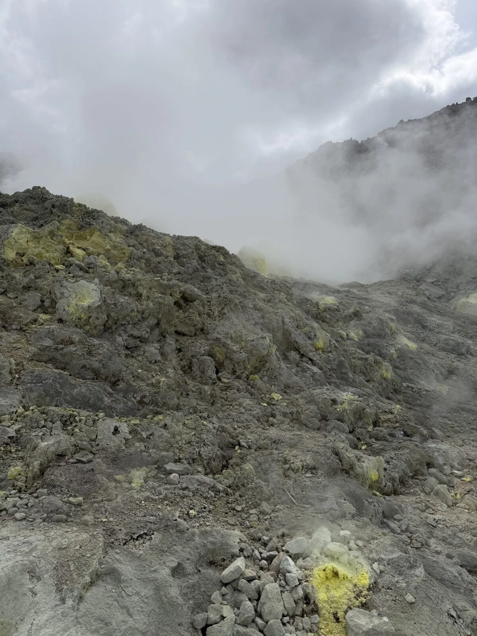 硫黄山の黄色い硫黄がついたごつごつした岩の斜面
