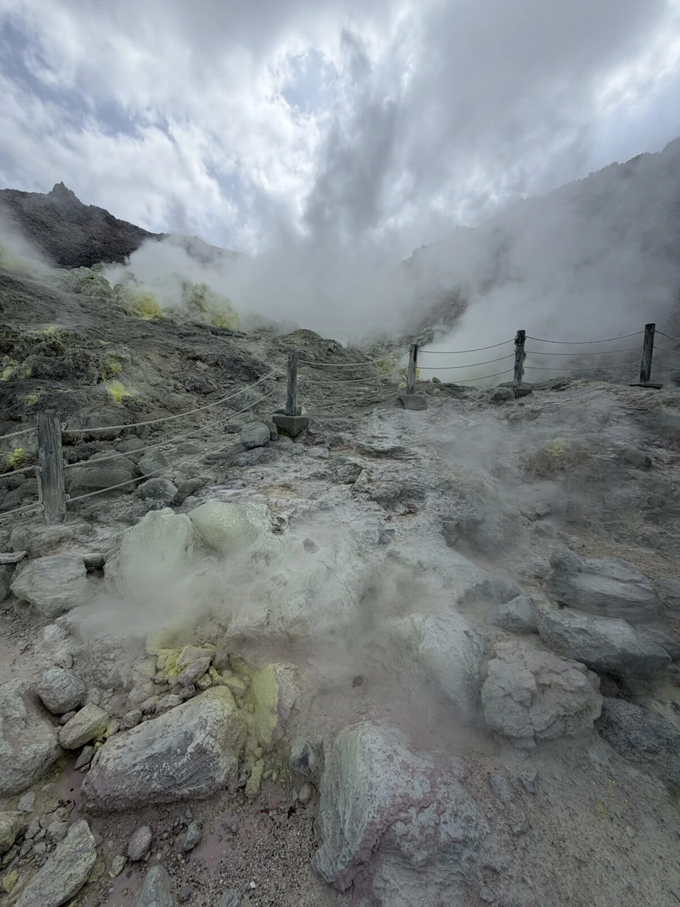 硫黄山のロープの柵の向こうで、岩場から噴き出す白い噴気