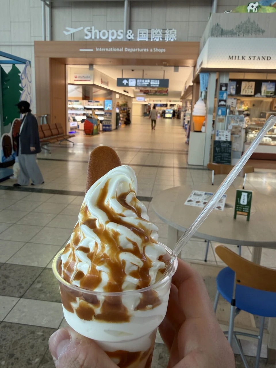 旭川空港のMILK STAND前で手に持ったキャラメルソースのソフトクリーム