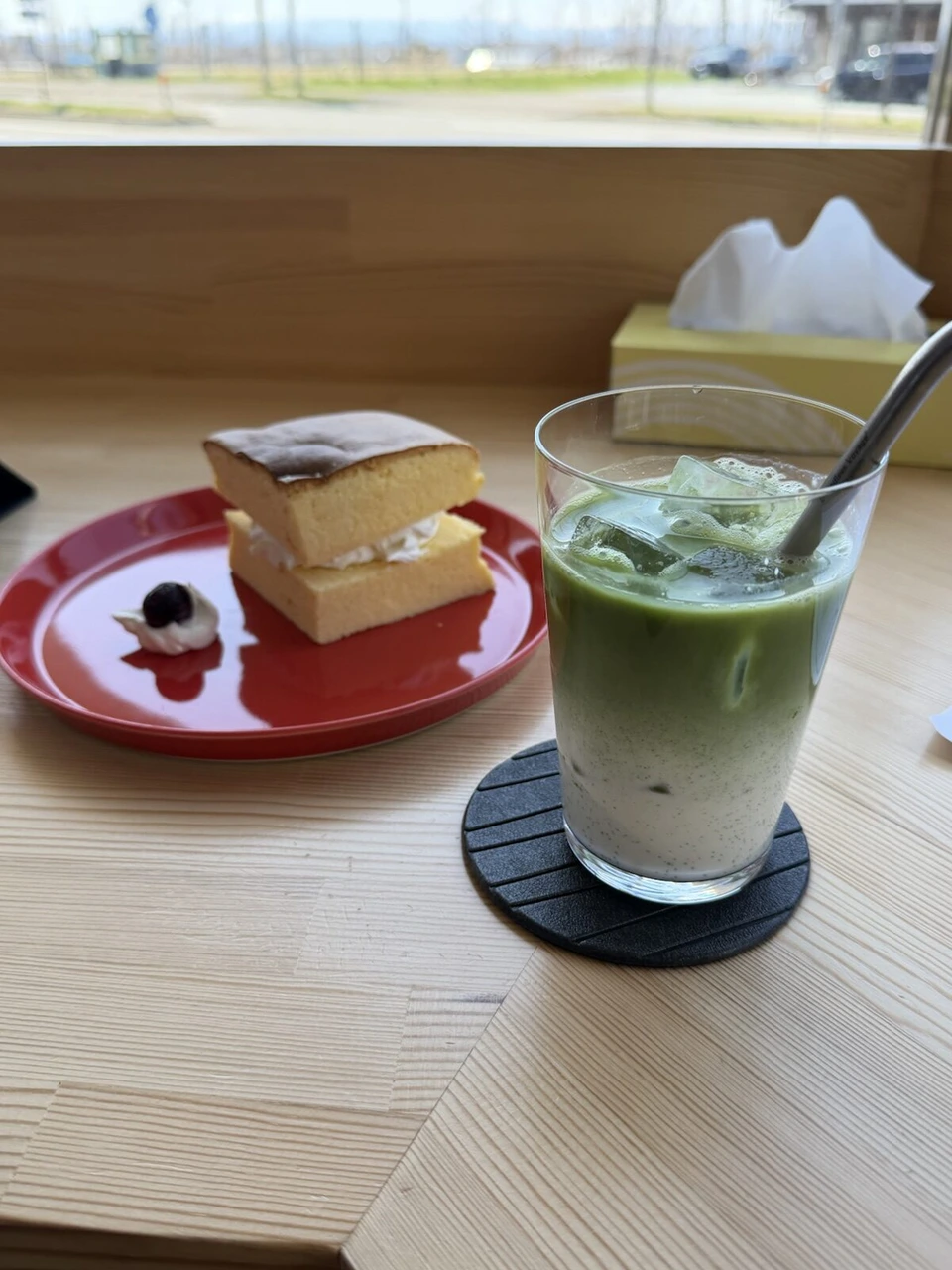 岩見沢・栗沢のantenna coffeeの窓際の席に置かれた抹茶ラテと、クリームを挟んだカステラのようなケーキ
