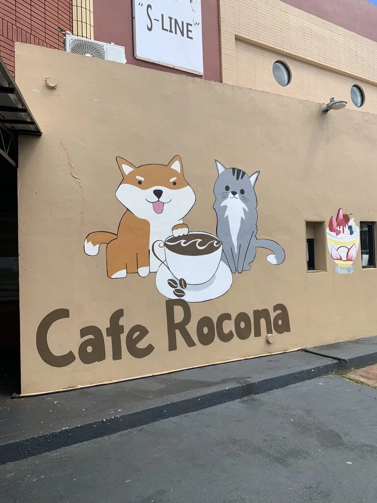 タモンのCafe Roconaの外壁。コーヒーカップを持つ犬と猫のイラスト