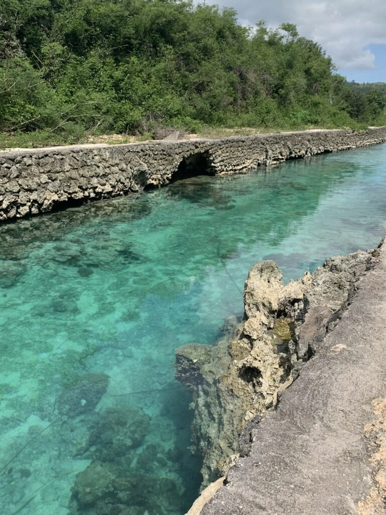 グアム南部の天然プールを岩の岸から見下ろした、底の岩まで見える水