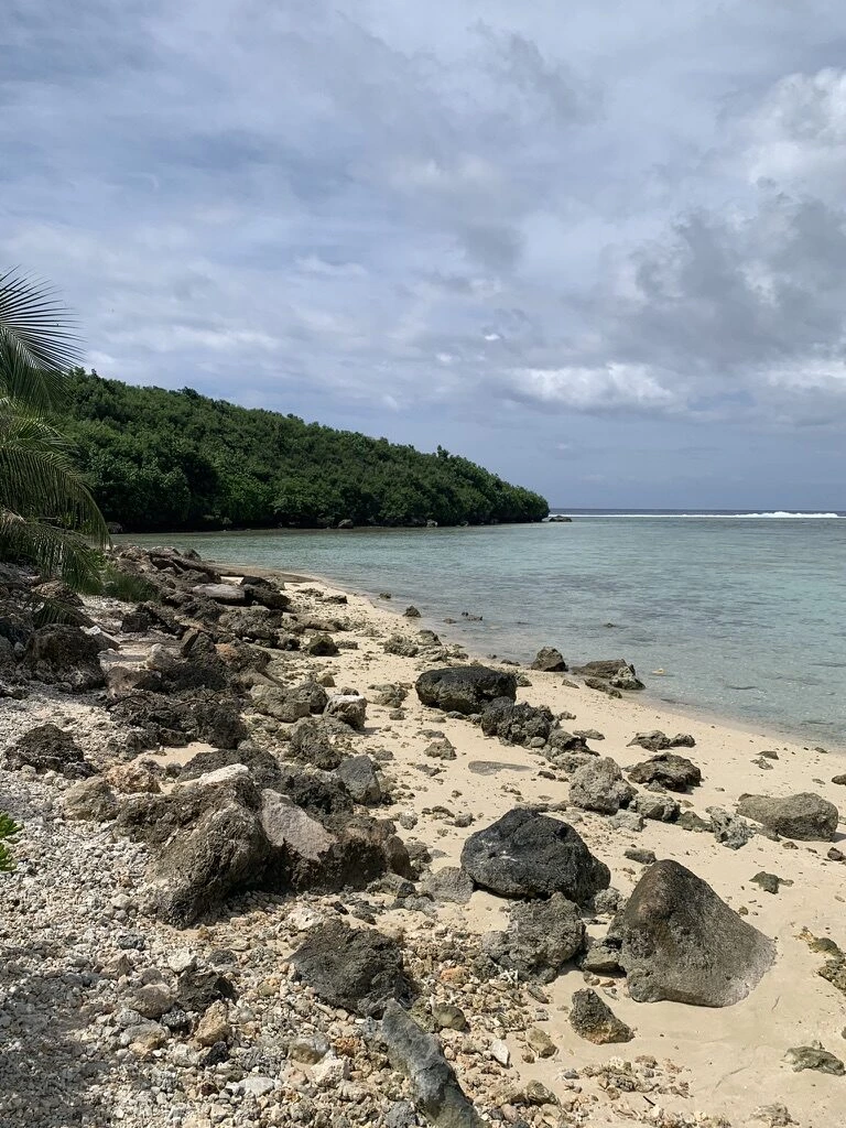 グアム南部の岩の転がる砂浜と、緑に覆われた岬