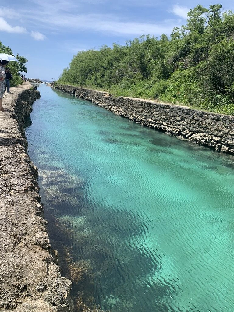 グアム南部の海沿いの天然プール。石積みの岸にはさまれた、まっすぐ延びるターコイズ色の水路
