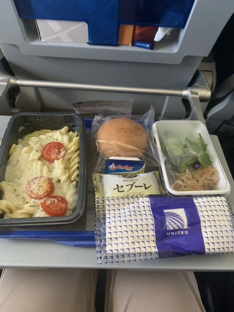 UA827の機内食。チーズとトマトのパスタ、パン、サラダ