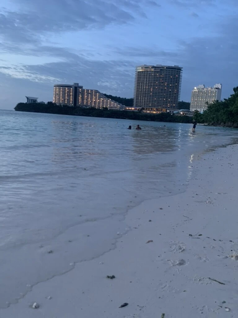 引き潮で広がったタモン湾の白い砂浜と、岬に立つホテル
