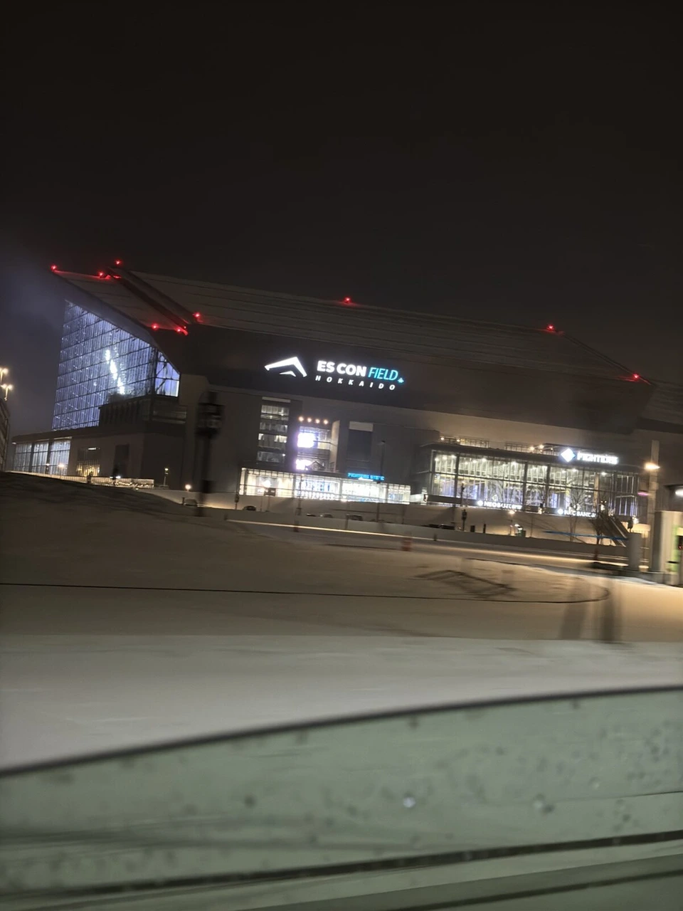 車の窓越しに見た、雪原の奥のエスコンフィールド全景