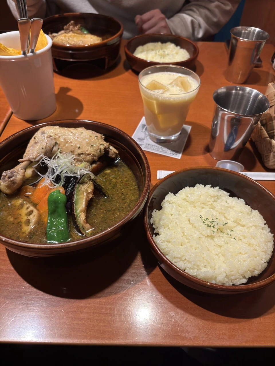 札幌駅の北側で食べたスープカレー。骨付きチキン、ピーマン、なす、れんこん、にんじん。横にライスとラッシー