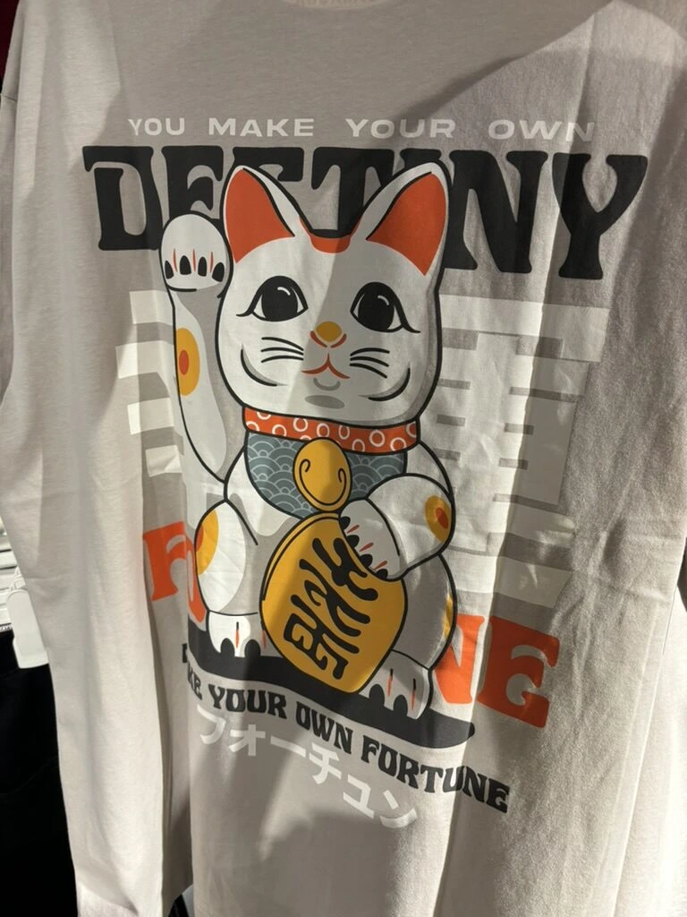 クアラルンプールの服屋に並ぶ、招き猫とフォーチュンの文字が入った白いTシャツ
