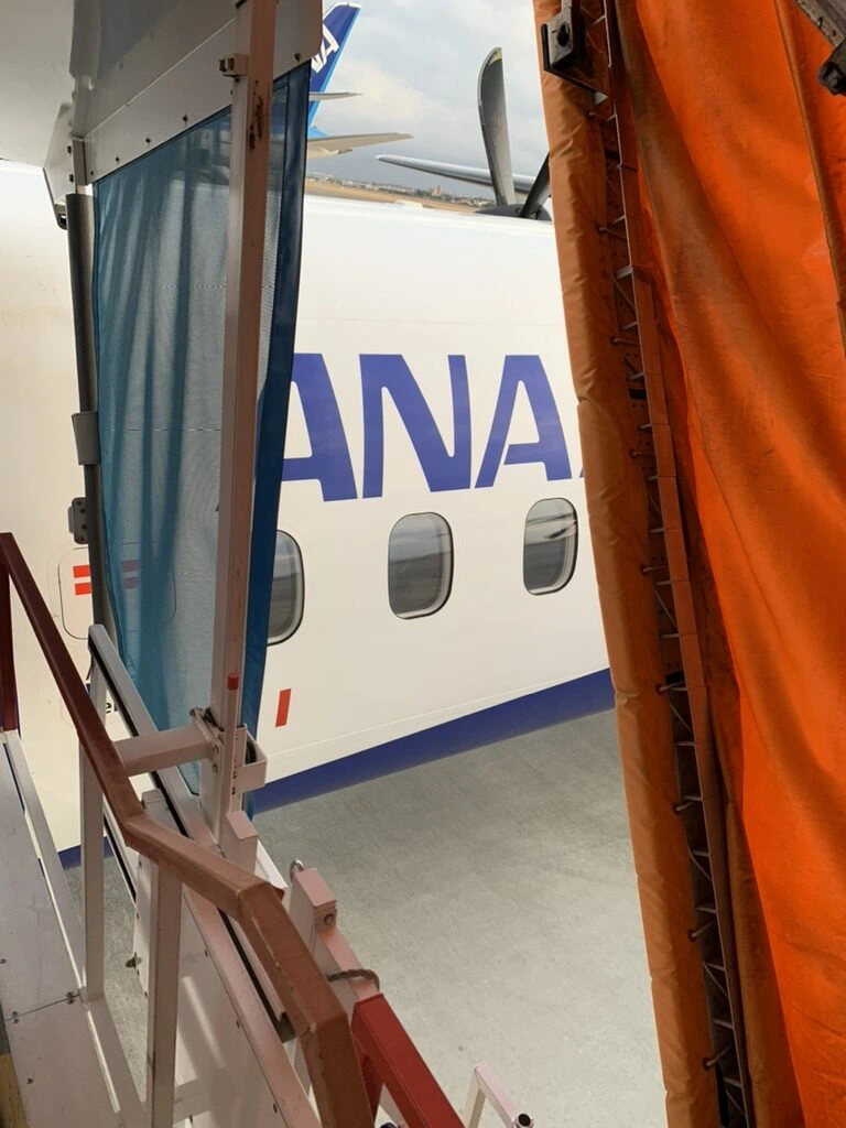 搭乗橋から階段で降りた先に見えるQ400の機体とANAのロゴ