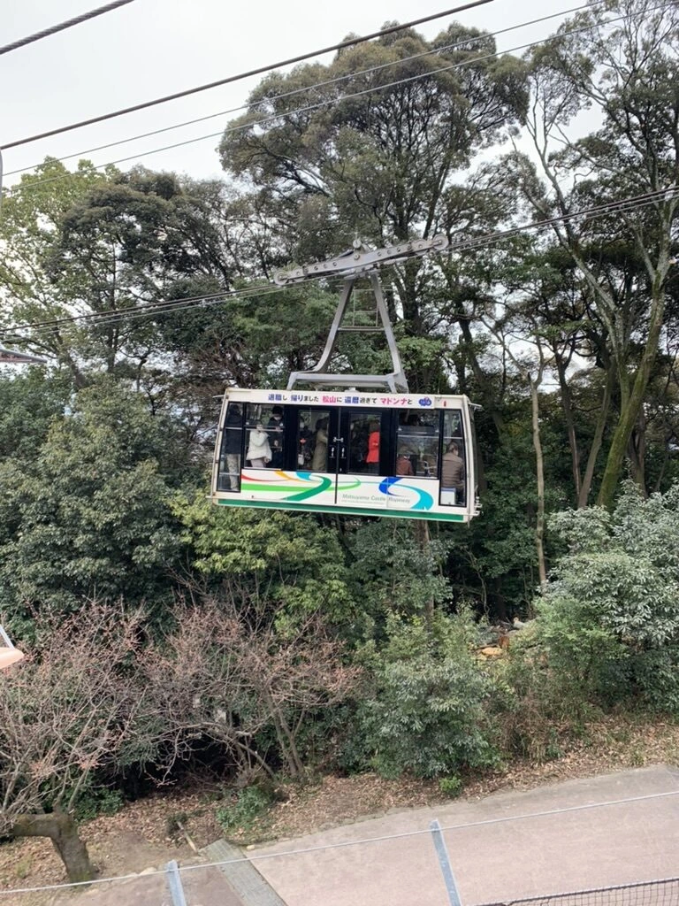 木々の間を下っていく松山城ロープウェイのゴンドラ