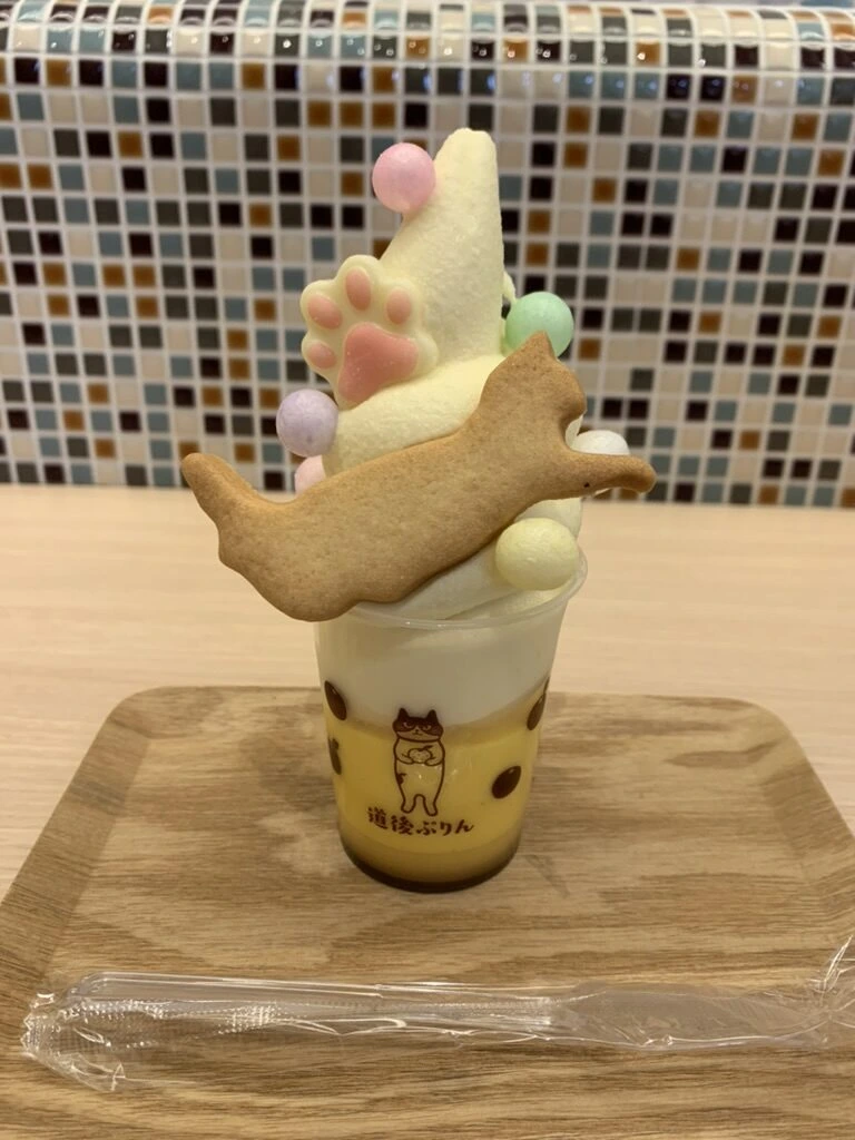 猫の形のクッキーと肉球の飾りがのったソフトクリームのパフェ。カップに道後ぷりんの文字