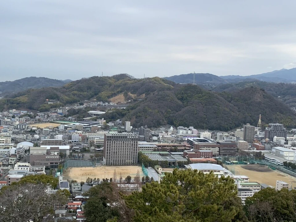 松山城から見た北側の山と、学校のグラウンドがある街並み
