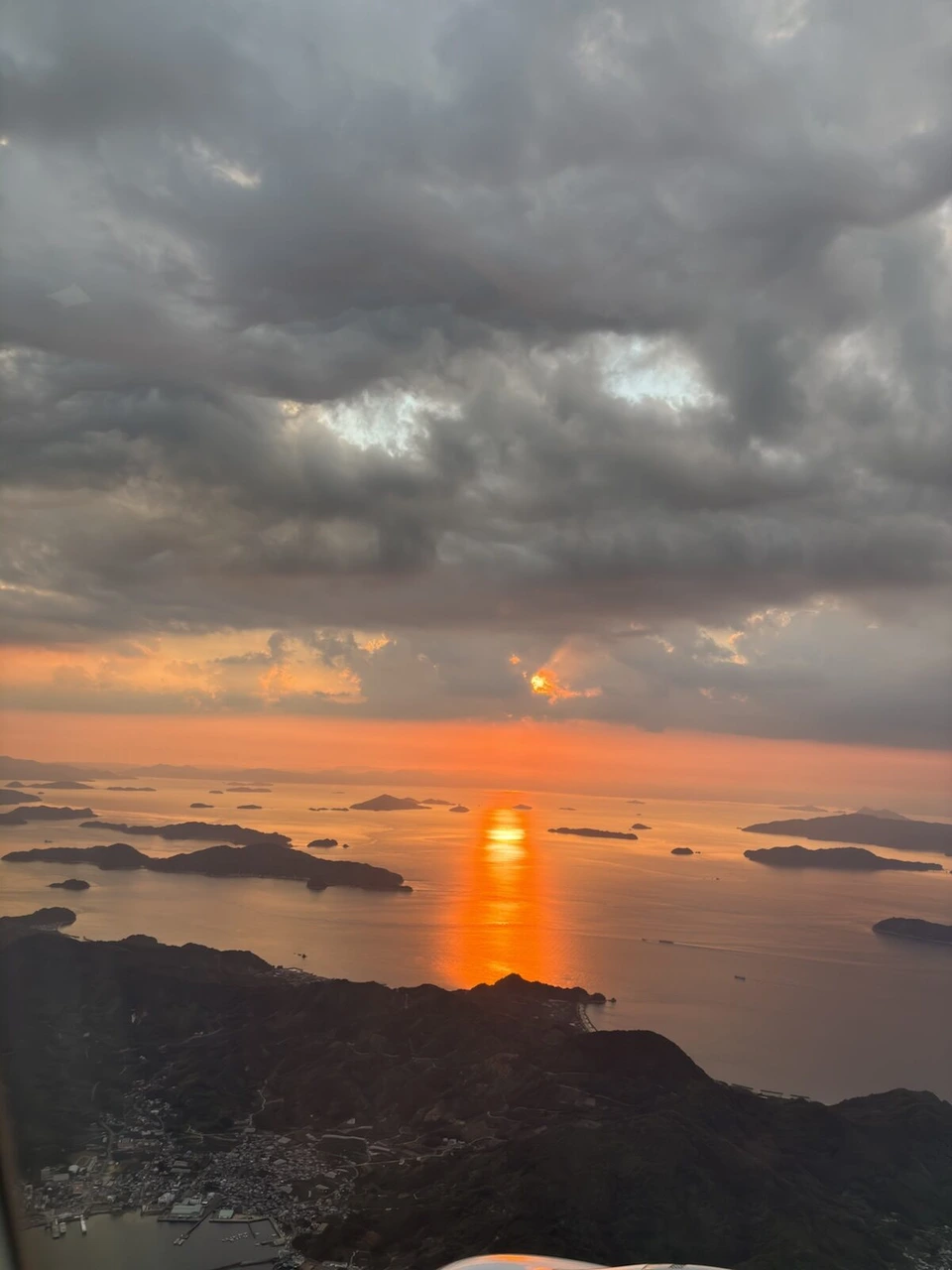 機窓から見た瀬戸内海の夕日。島々の間の海に太陽が細長く映っている