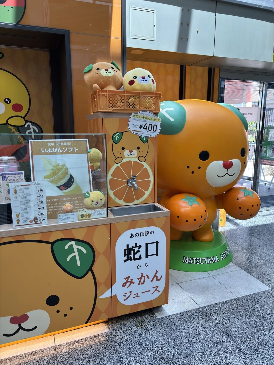 松山空港の蛇口からみかんジュースのスタンド。1杯400円の表示とみきゃんの大きな像
