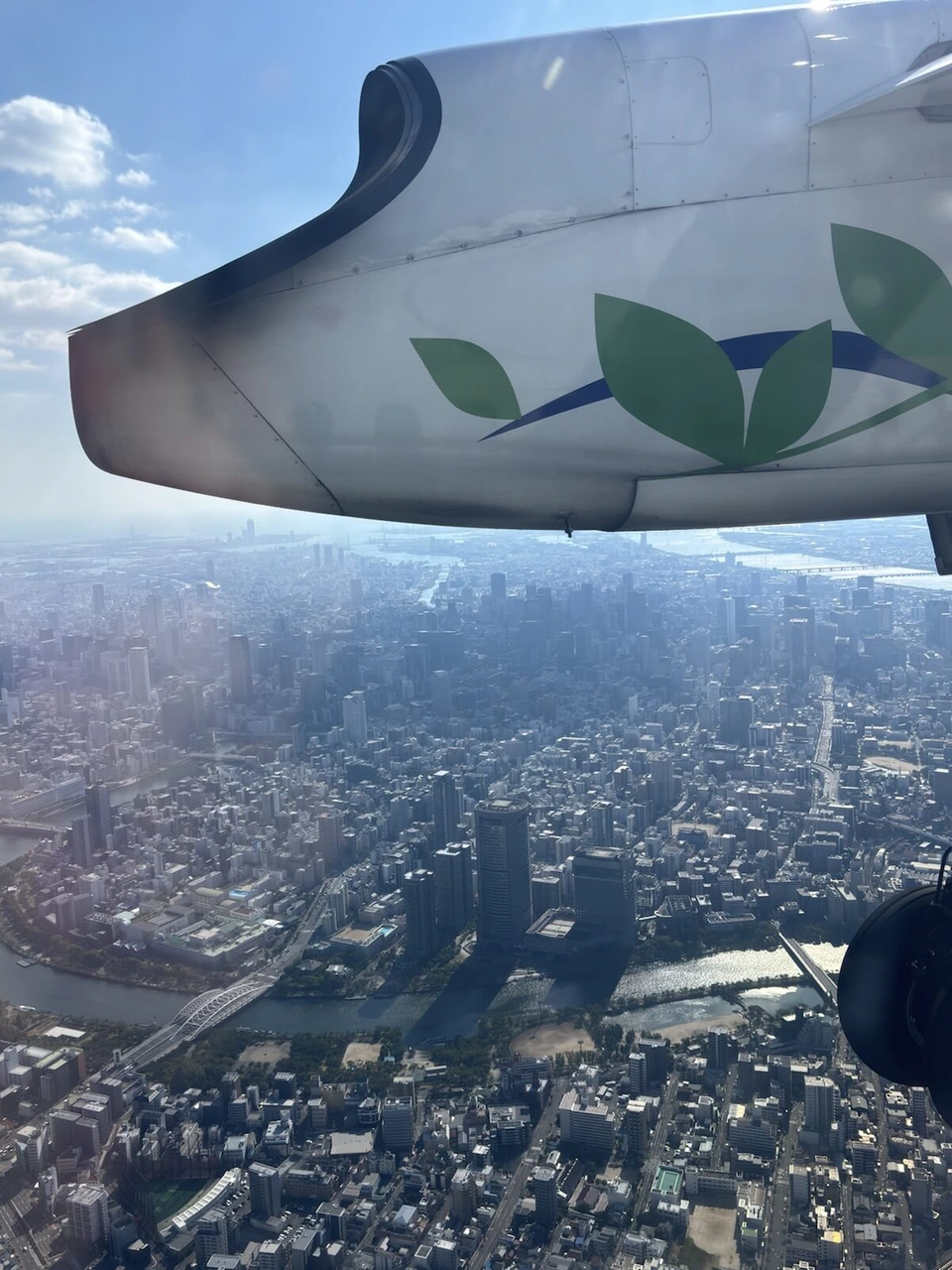 Q400の窓から見た大阪市街の上空。川沿いの高層ビルとアーチ橋