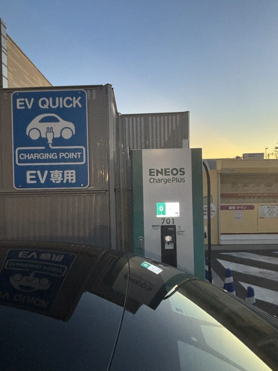 長崎空港の駐車場にあるEV急速充電器と、夕焼けの空
